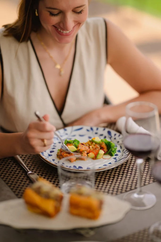 Una chica feliz en una mesa observa un plato muy sabroso que le han servido en restaurante CBbC Marina Sta. Eulalia