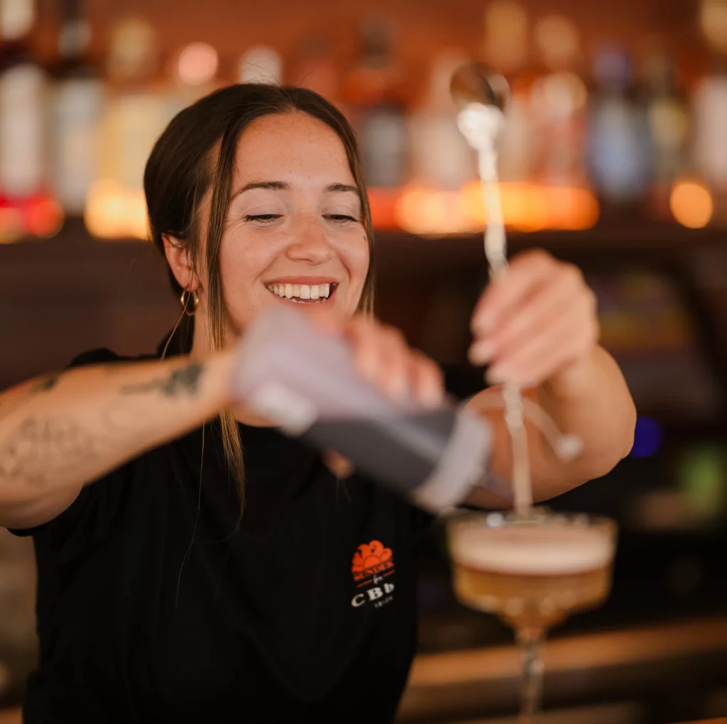 Una camarera sonriendo preparando un cóctel en Cala Bassa Beach Club