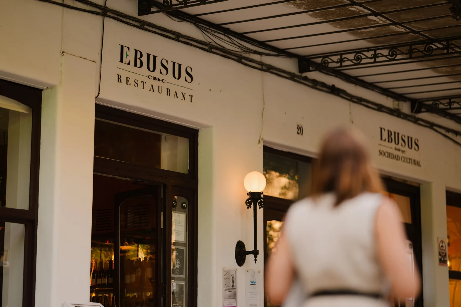 Una chica pasea por delante de eBUSUS restaurante, en Ibiza, en Vara del Rey